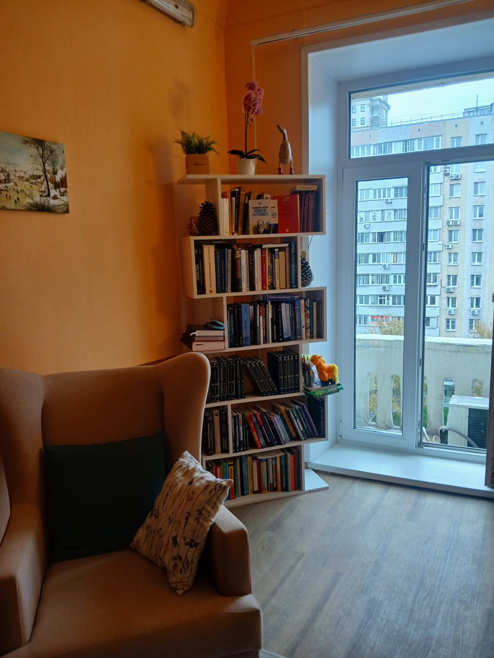Книжная полка и кресло у окна в кабинете
